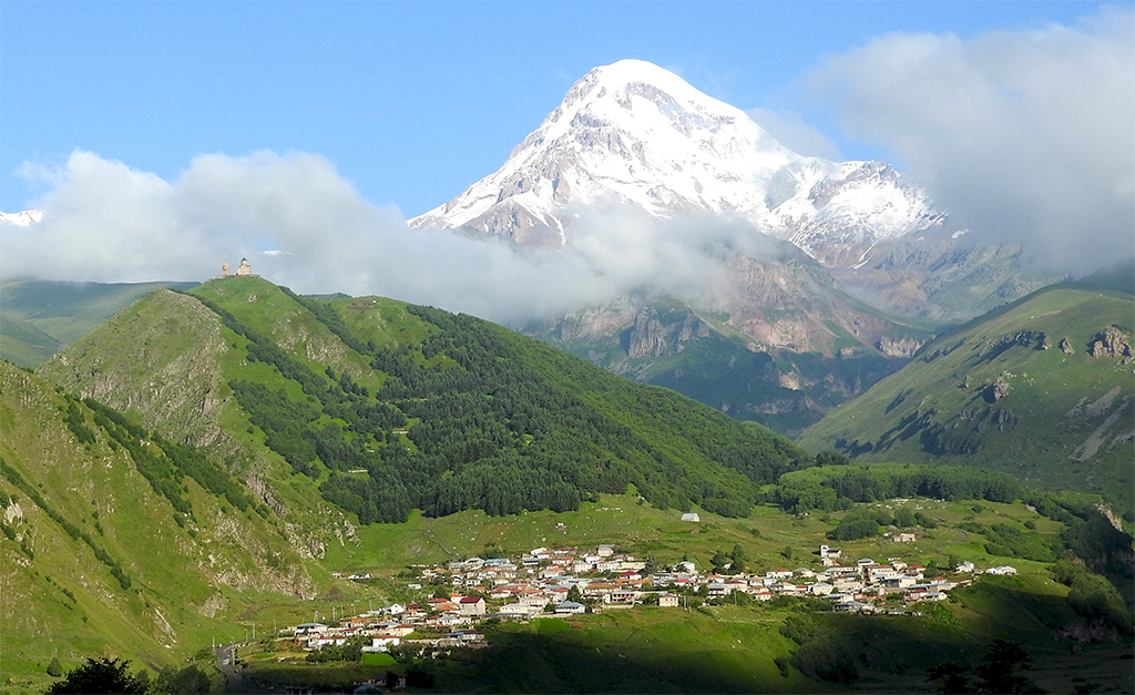 A Mount Kazbek, előtte a Gergeti Trinity Templom és Stepantsminda települése.